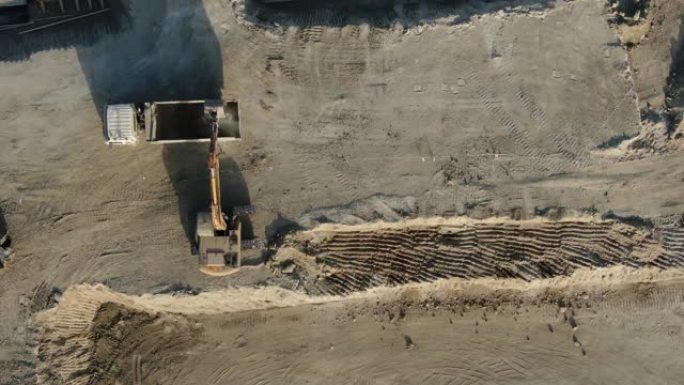 用挖掘机将土壤装载到自卸车中的施工地块。沿坑边缘的重型车辆路径。生产阶段