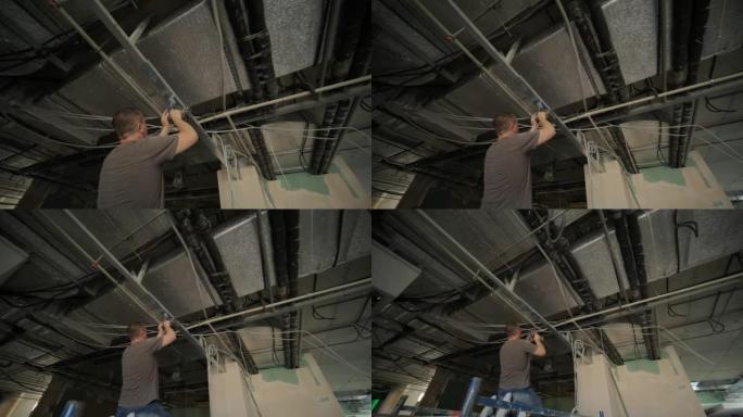 建筑工人组装一个带有干墙的吊顶，并用螺丝刀将干墙固定在天花板金属框架上。翻新、建造和自己动手DIY概