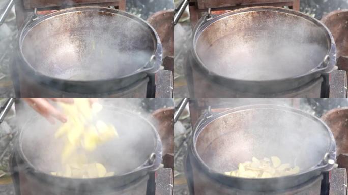 在大自然的大锅中烹饪。厨师倒油，把土豆放在火上的锅里