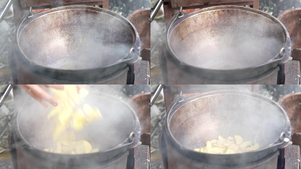 在大自然的大锅中烹饪。厨师倒油，把土豆放在火上的锅里