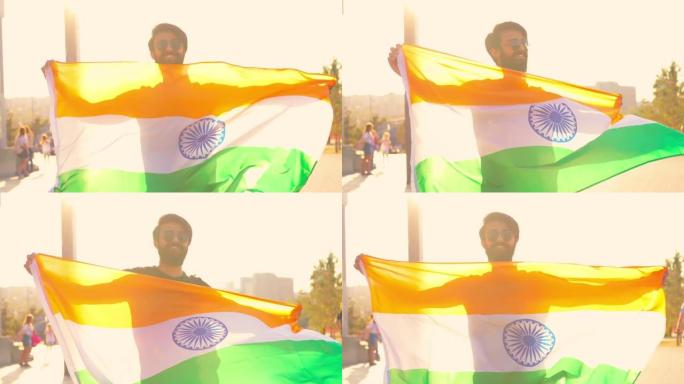 英俊的印度大胡子男子，穿着黑色棉t恤，在夏日公园的夕阳下挥舞着印度国旗。