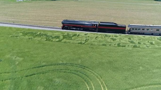 晴天穿越农田的古董蒸汽旅客列车的空中平行视图