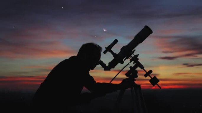 闪烁的夜空下的男人，望远镜和乡村的轮廓。