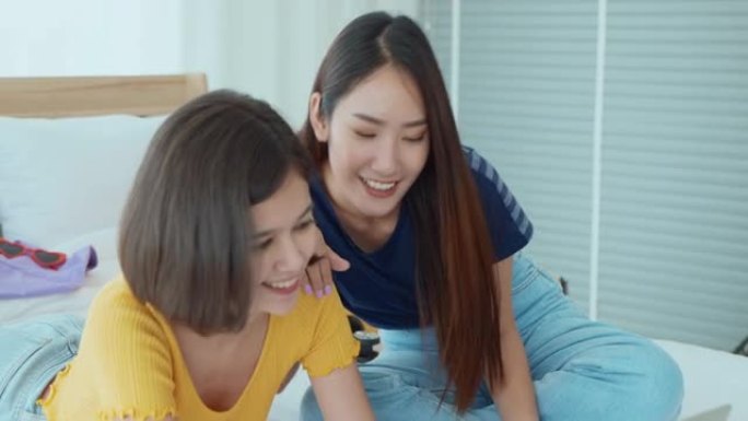 两名坐在床上的年轻女子在网上预订运费后感到高兴。