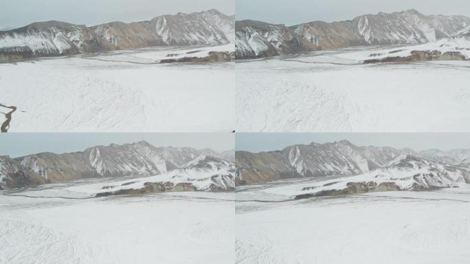 无人机在积雪覆盖的山脉上，下面是辫状河