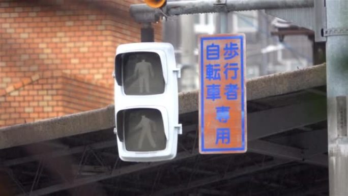步行标志在雨中闪烁着日语的文字