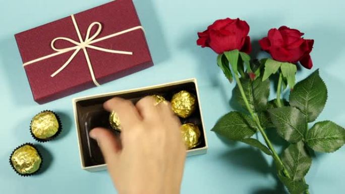 女人将金色优质巧克力糖果放入带有红玫瑰花朵的礼品盒或礼品盒中，为情人节做准备，节日概念