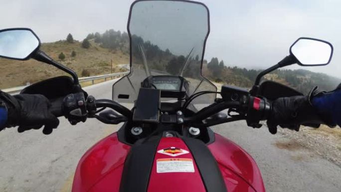POV骑摩托车的人在多云有雾的天气下在高山山口骑摩托车