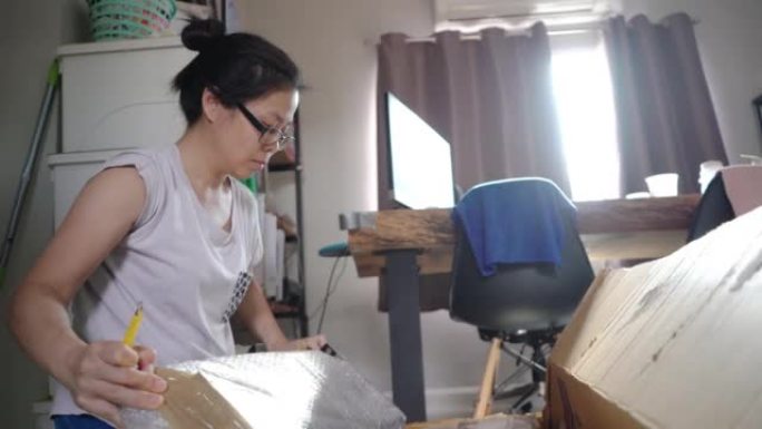 亚洲妇女在家里的盒子里打开家具的包装。