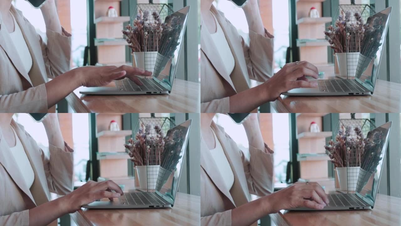 Close up 4k of woman hands正在键入计算机笔记本电脑，以便在咖啡店的木制柜台