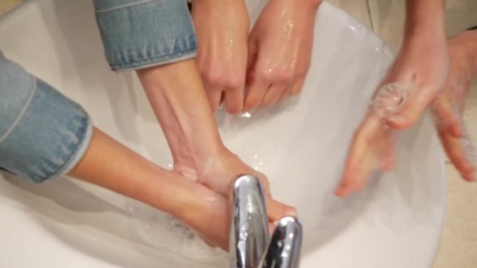 三个十几岁的孩子女孩姐妹在浴室的盥洗台上用肥皂洗手俯视图特写