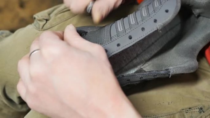 鞋匠的手从运动鞋的接缝上取下旧线