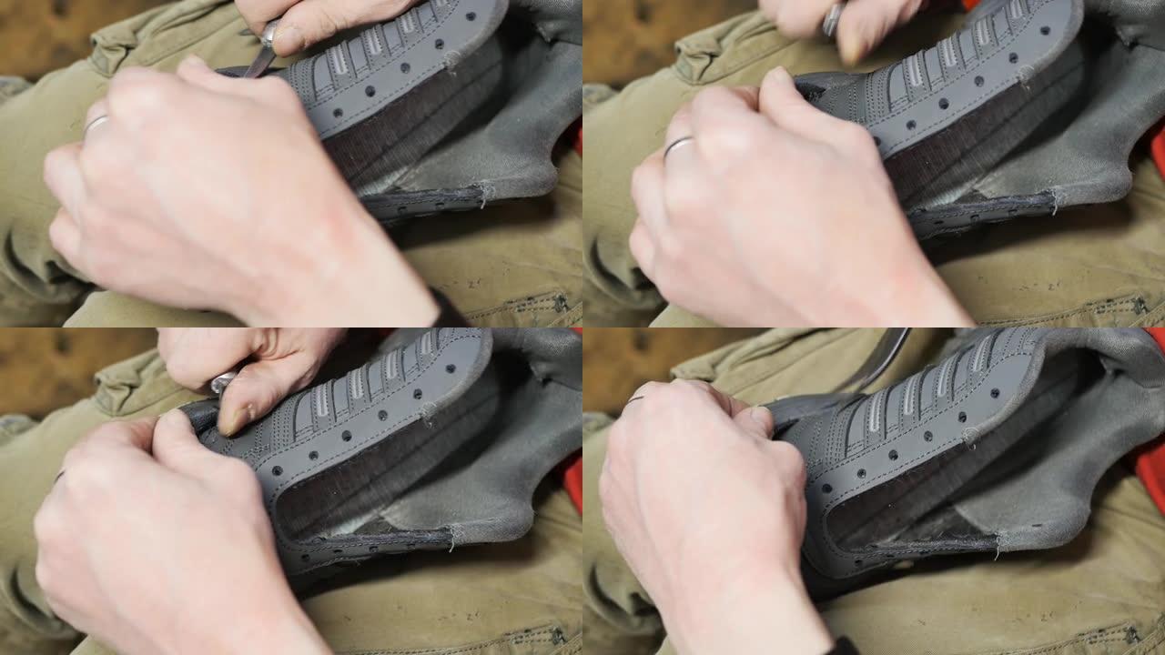 鞋匠的手从运动鞋的接缝上取下旧线