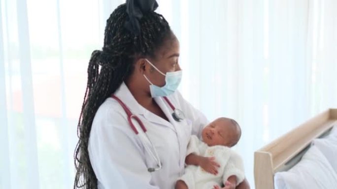 带卫生口罩的非裔美国医生将新生婴儿抱在胸前，看起来像摇篮曲婴儿在床上，房间里有白色窗帘