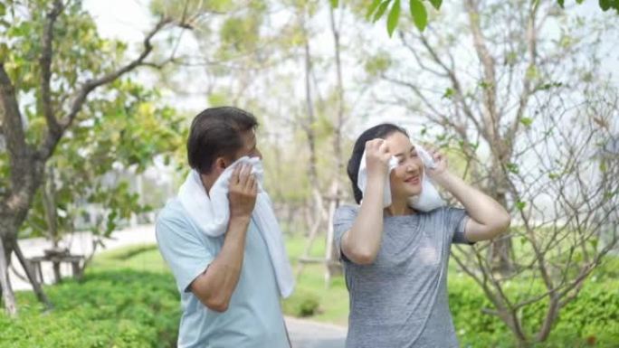 健康的生活方式和运动。亚洲幸福成熟夫妇丈夫在公园跑步后擦汗。快乐的老年夫妇在公园慢跑。
