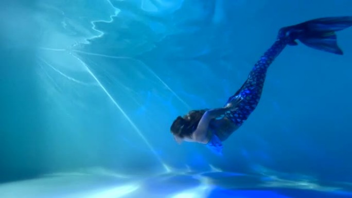 美人鱼尾巴的女人在水下游泳和潜水。