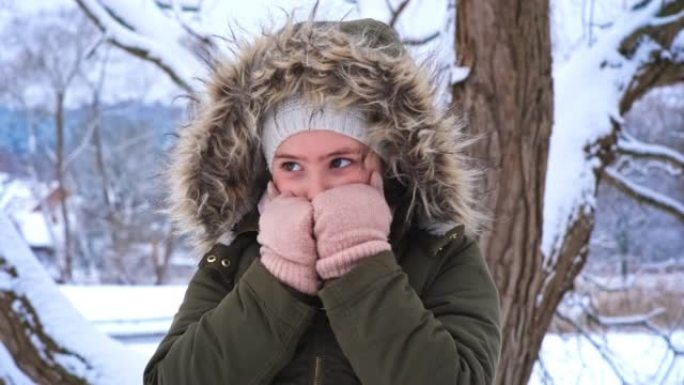 美丽的年轻高加索女孩穿着温暖的冬季夹克和手套站在寒冷的下雪天户外