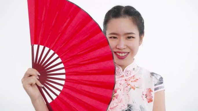 中国/亚洲美女在春节与红扇，微笑着看着镜头