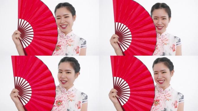 中国/亚洲美女在春节与红扇，微笑着看着镜头