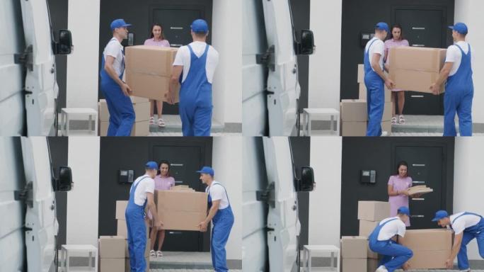 搬迁公司的两名年轻工人将箱子和家具从小巴上卸下到客户家中
