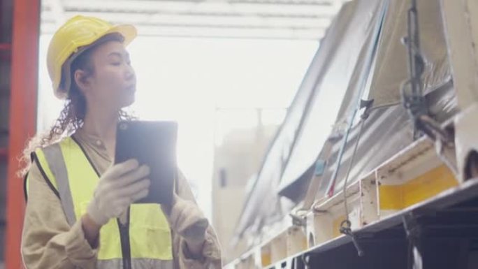 在钢铁工业仓库工作的亚洲女工。女主管根据平板电脑的订单检查钢制零件的数量，这些零件在金属钢制造的生产