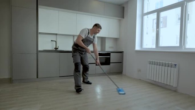 一个穿着制服的开朗工人在新公寓里洗地板