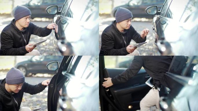 偷车贼正在偷车。黑进汽车系统。兜帽男试图用平板电脑破坏汽车的安全系统