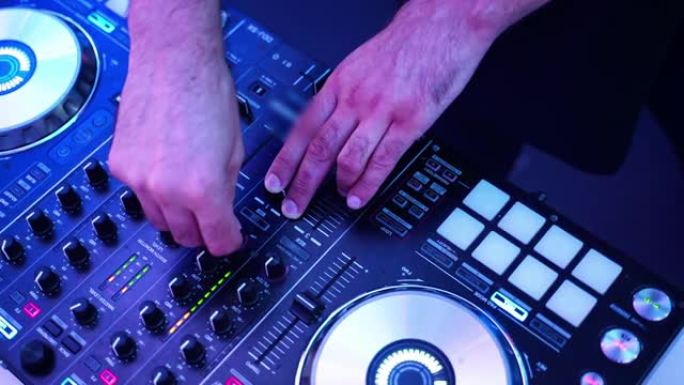 DJ的手的特写扭曲并按下DJ遥控器上的不同按钮，俱乐部中的色彩和轻音乐。与dj聚会