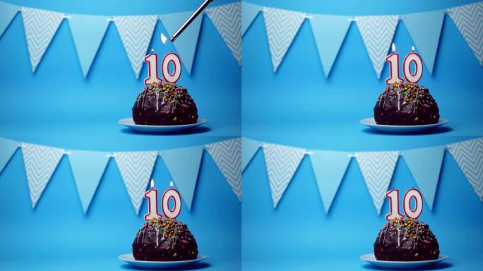 巧克力生日蛋糕，蓝色背景上燃烧着10号，10号蜡烛。复制空间。文本的位置