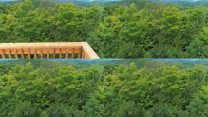 无人机视图从watch望塔的木栏杆后面升起，露出平台周围的树林
