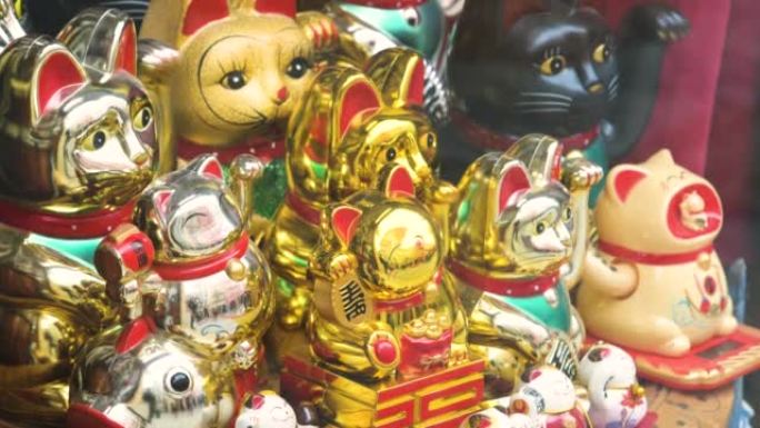 商店陈列的多个传统日本maneki neko召唤猫移动爪子小雕像，一组物品，商店出售的旅游纪念品，展