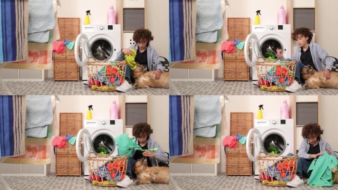 家务。男孩在家洗衣服，把衣服装进洗衣机，和狗一起玩