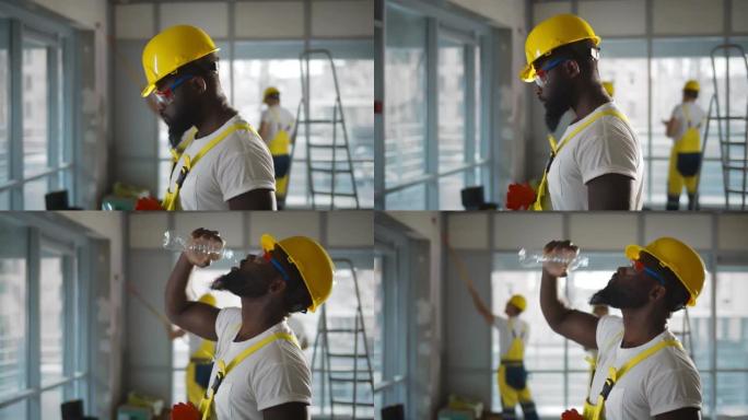 疲倦的非裔美国建筑工人喝水