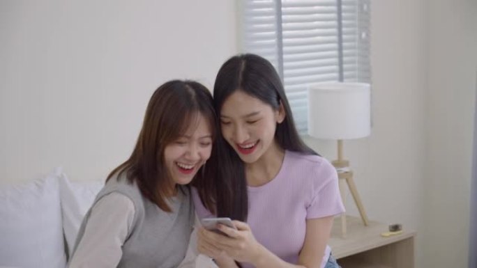 漂亮的亚洲年轻人在床上的社交媒体上玩得很开心。两个十几岁的女孩在手机上看到短信时很高兴。生活方式概念