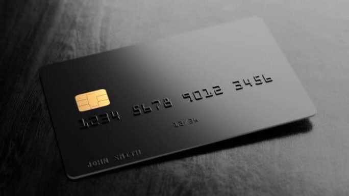 一张带有假号码和名字的黑色信用卡以慢动作落在黑色木桌上。