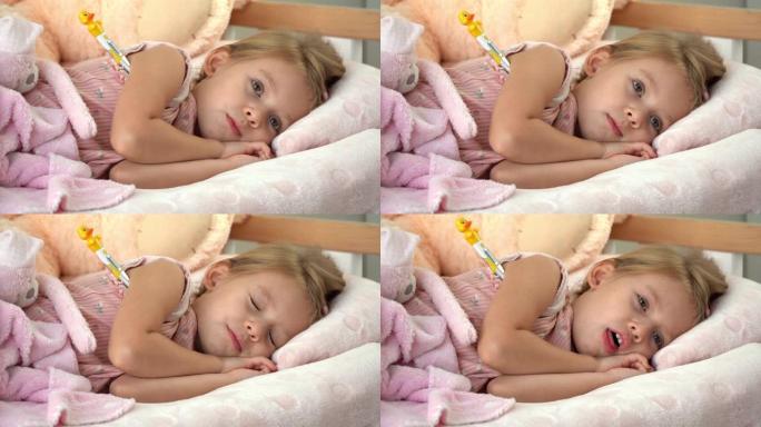 生病的小孩躺在床上，体温计看着相机，咳嗽。疾病中的温度测量。流感和感冒的治疗