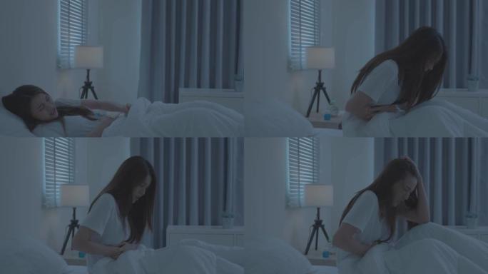 穿着睡衣的亚洲漂亮女孩坐在卧室的床上感到恶心。迷人的睡眠年轻女子触摸腹部感觉不好，发热和胃痛早上在家