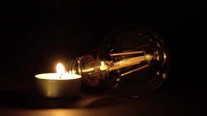发光二极管灯泡旁边点燃的一根茶灯蜡烛