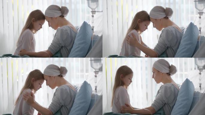 与小女儿坐在医院病床上的癌症年轻女子的侧视图
