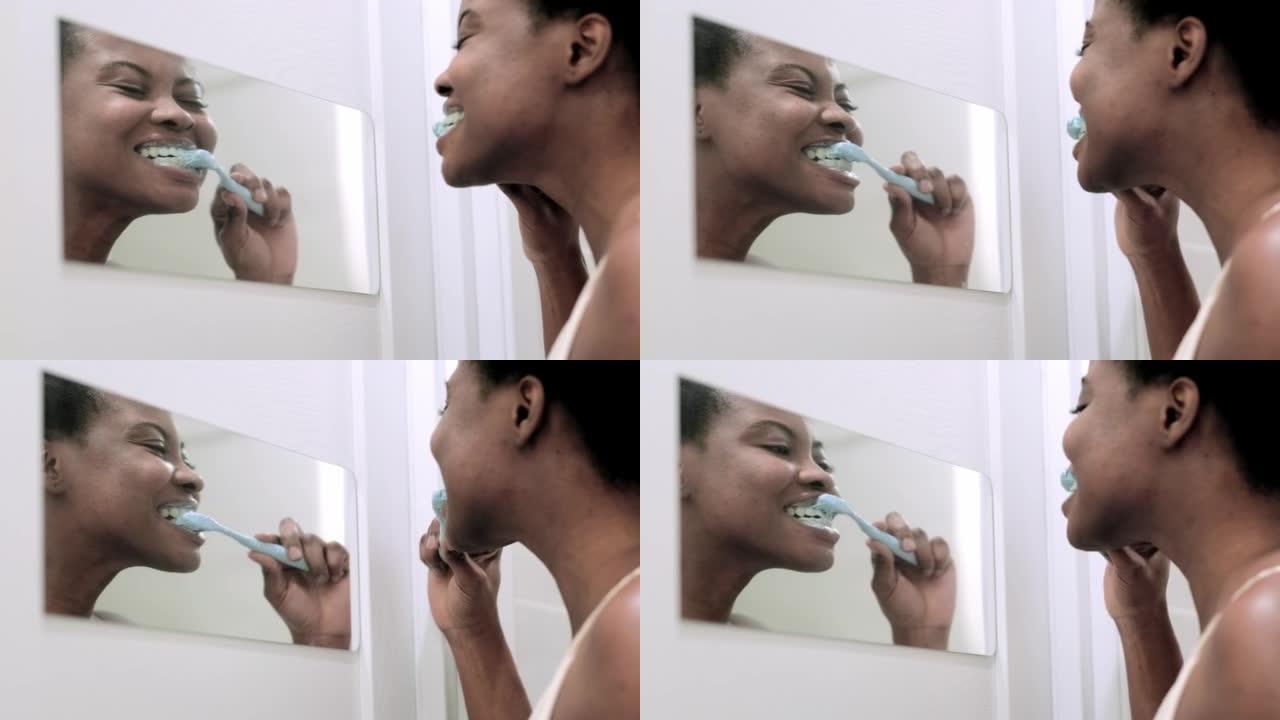 肖像快乐黑人非洲裔美国女孩在浴室刷牙。早上用牙刷照镜子的女人