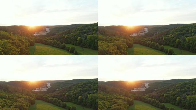 用无人机在捷克卡尔斯泰因上空拍摄的神奇日落。著名的堡垒建在森林中的山顶上。夏天的天气，柔和而温暖的光