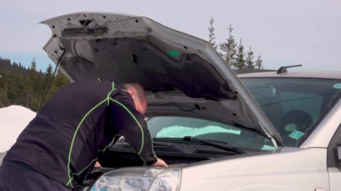 男子在冬季山区修理或修理损坏的汽车