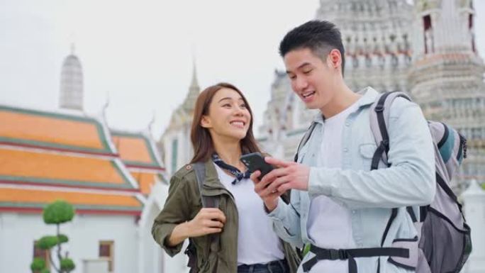 亚洲迷人的浪漫情侣在城市里度蜜月旅行。新婚姻男女背包客游客使用手机寻找目的地，一起享受假期。