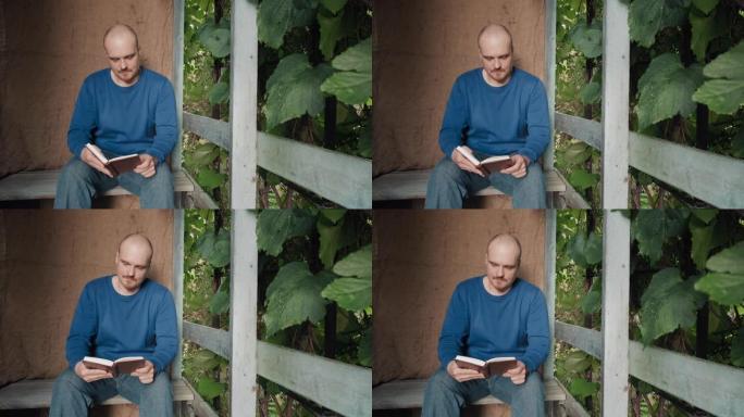 男人正在读一本坐在村舍门廊上的纸质书