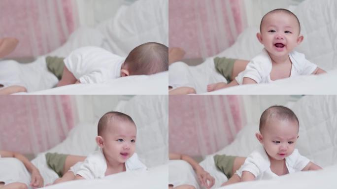 可爱的亚洲新生男婴躺在白色床上玩耍，笑容满面。而你妈妈在附近照顾。小天真的新生婴儿可爱的孩子在生命的
