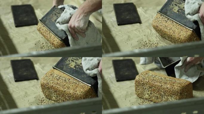 面包师的手从烤盘中取出新鲜出炉的带芝麻的面包面包