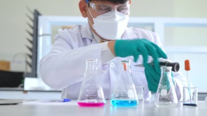 亚洲男性医学科学家研究人员穿着实验室外套和防护设备，在寻找潜在的新型冠状病毒肺炎疫苗时，仔细检查，测