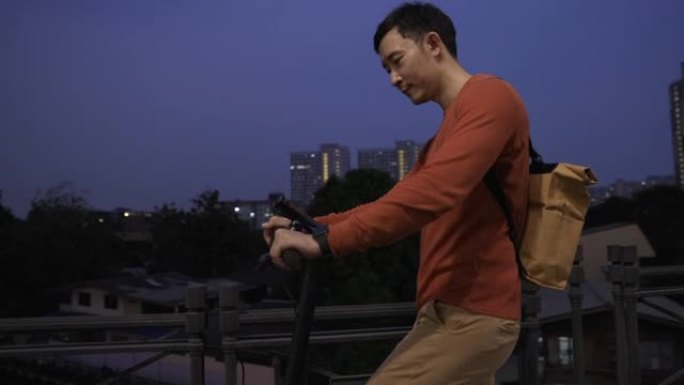 夜间生活方式亚洲男子骑电动推踏板车过桥