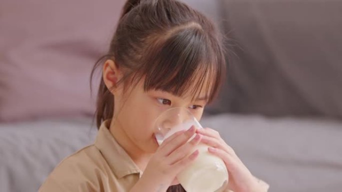 快乐的亚洲孩子在家喝新鲜牛奶，身体健康。享受美味，强壮的骨头。女孩子喝杯豆浆，含钙可口。健康的生活方