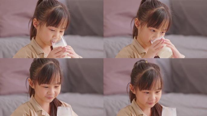 快乐的亚洲孩子在家喝新鲜牛奶，身体健康。享受美味，强壮的骨头。女孩子喝杯豆浆，含钙可口。健康的生活方